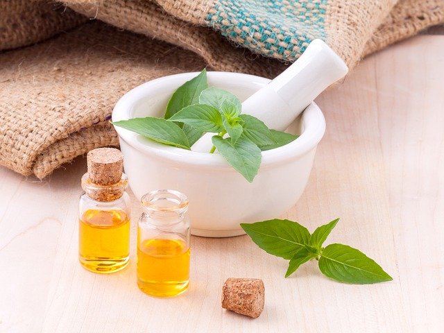 A white mortar and pessel with herbs and oils