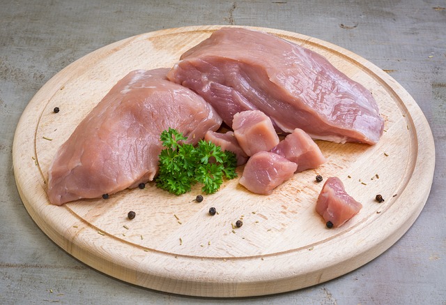 Raw meat chicken breast with a sprig of parsley on a wood platter