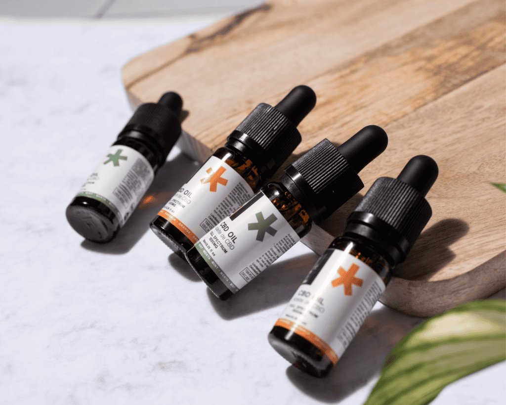 CBD oil bottles for dog cancer support on a wooden board.